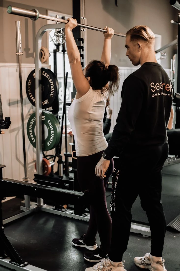 Coach kijkt mee bij overhead press